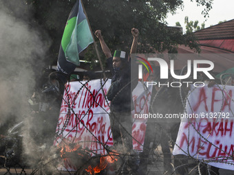 Indonesian students shout slogans and burn tires during the protest against a new labor law, which they fear will benefit investors at the e...
