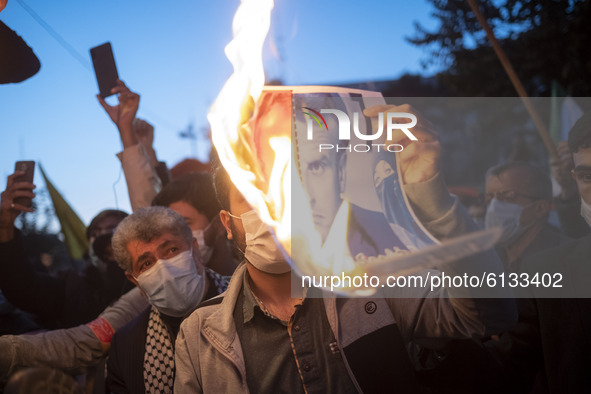 An Iranian protester burns a portrait of the French President Emmanuel Macron during a protest gathering in front of the French embassy in T...