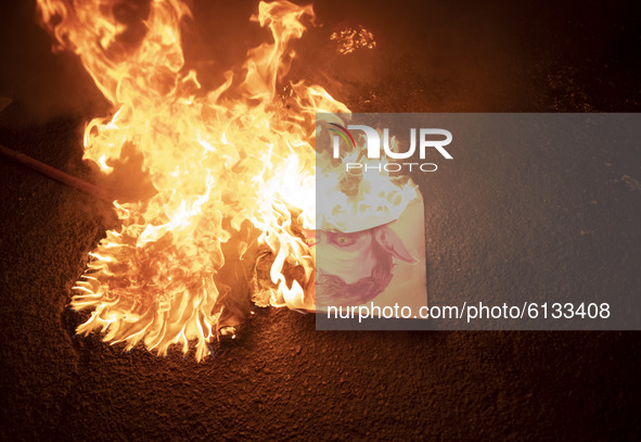 Iranian protesters burn a cartoon of the French President Emmanuel Macron during a protest gathering in front of the French embassy in Tehra...