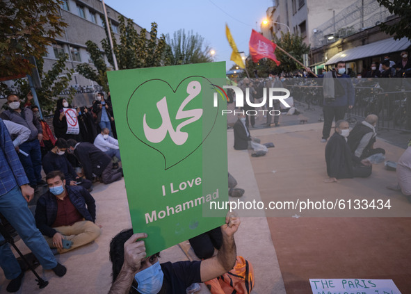 An Iranian protester holds-up a placard during a protest gathering in front of the French embassy in Tehran on October 28, 2020. Protesters...