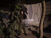 A member of the Iranian special police force looks on as he stands guard near the French embassy during a protest gathering in Tehran on Oct...