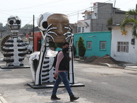 A person wears face mask while walks front a monumental skull made of cardboard,  were put to decorate the streets Of Tlahuac to celebrate D...