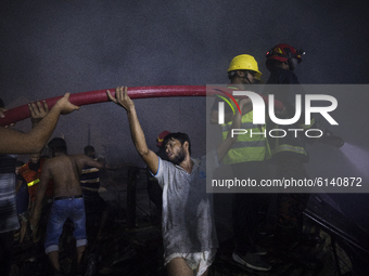 Residence and firefighters work to extinguish a fire that broke out in a slum in Dhaka on October 30, 2020.  (