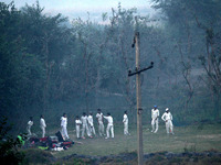 Cricketers warm up before a practice session amid a layer of smoky haze, as the air quality of the national capital hit 'very poor' levels d...