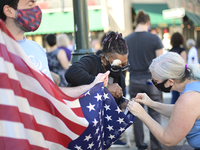 Karen Howard and Adina Silberstein repair an American flag to celebrate the historic victory of Joe Biden and Kamala Harris in the 2020 US P...