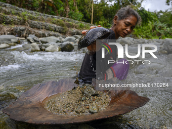 A mother takes sand from the bottom of a river for traditional panning in Powelua Village, Donggala Regency, Central Sulawesi Province, Indo...