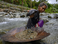 A mother takes sand from the bottom of a river for traditional panning in Powelua Village, Donggala Regency, Central Sulawesi Province, Indo...