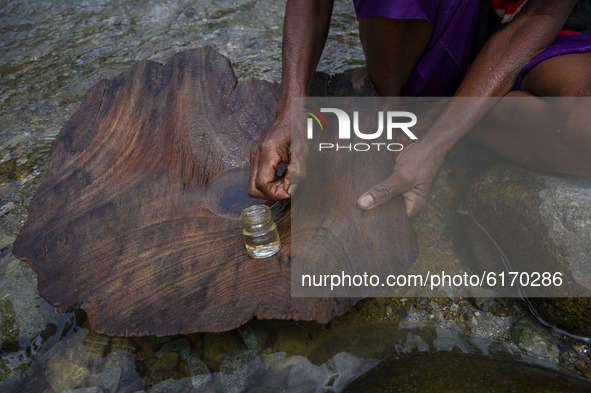 A mother picks up gold ore from her traditional pan in Powelua Village, Donggala Regency, Central Sulawesi Province, Indonesia on November 8...