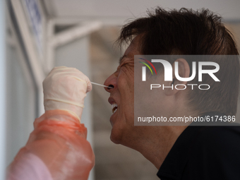 A health worker wearing personal protective equipment (PPE) perform Covid-19 nasal swab testing through protective mobile unit on people at...