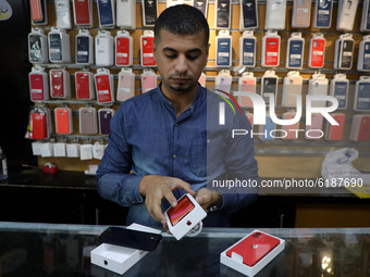A Palestinian man holds Apple's new iPhone 12 at a mobile phone store in Gaza City on November 14, 2020. Apple's new iPhone 12 is selling we...