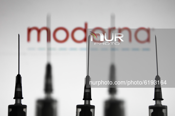 Medical syringes are seen with Moderna company logo displayed on a screen in the background in this illustration photo taken in Poland on No...