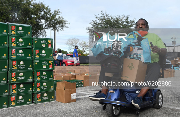 A man on a motorized wheelchair carries food donated by the Second Harvest Food Bank of Central Florida and the City of Orlando at Jones Hig...