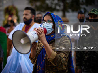 A woman dressed in Malahfa and wearing a face mask talks with a mehgaphone during a demonstration to demand the end of Morocco's occupation...