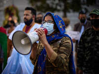 A woman dressed in Malahfa and wearing a face mask talks with a mehgaphone during a demonstration to demand the end of Morocco's occupation...