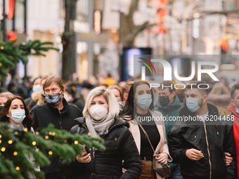 people with face masks walk in the city center of Cologne, Germany, on November 21, 2020 as Christmas lights are seen. (