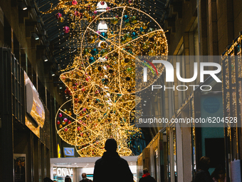a man walks under the Christmas decoration in neumarkt Galerie shopping mall in Cologne (