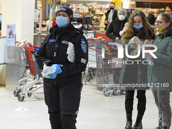 Estonian Police officer distributing free face masks to visitors of shopping mall in Narva. Wearing masks indoor of public spaces and transp...