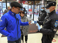 Estonian police officer (R) giving the free mask to shopping mall visitor in Narva, third largest city of Estonia. Wearing masks indoor of p...
