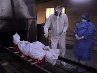 Family members wearing Personal Protective Equipment (PPE) perform last rites of a person who died of coronavirus (COVID-19) before a cremat...