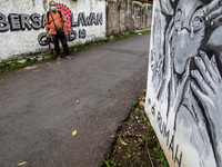A photo journalist wait for people passing by the mural to take photos. Mural about Covid19 at Bintaro South Tangerang, Banten, Indonesia. I...