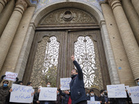 A protester gestures as the other protesters hold placards during a protest gathering against the assassination of the Iranian Top nuclear s...