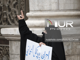 A female veiled protester gestures as she holds a placard with a Persian script that said, Implement the NPT must be stope, during a protest...