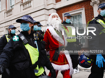An anti-lockdown activist dressed as Father Christmas is arrested in Grosvenor Square during a demonstration in London, England, on November...