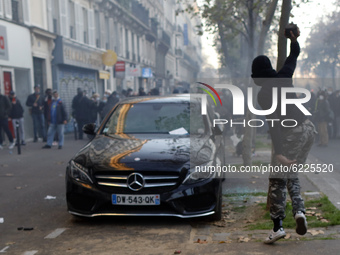 A man breaks a car in Paris on November 28, 2020 during a protest against the ''global security'' draft law, which Article 24 would criminal...