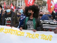 Assa Traore (C), the sister of late Adama Traore, a man who died in police custody, stands behind a banner at the Place de la Republique in...