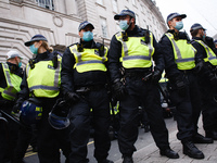 Police officers in riot gear form a cordon amid scuffles with activists on Regent Street during an anti-lockdown demonstration in London, En...