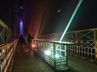 People walk on a illuminated bridge during cold winter evening in Srinagar, Indian Administered Kashmir on 30 November 2020. (