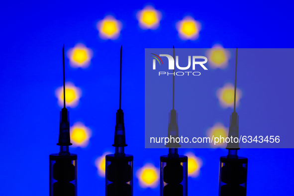 Medical syringes are seen with European Union flag displayed on a screen in the background in this illustration photo taken in Poland on Jan...