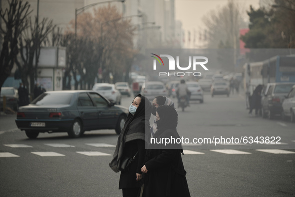 Iranian women wearing protective face masks cross an avenue in northern Tehran during a polluted air, following the COVID-19 outbreak in Ira...