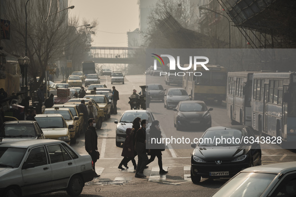 Iranian people wearing protective face masks cross an avenue in northern Tehran during a polluted air, following the COVID-19 outbreak in Ir...