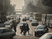 Iranian people wearing protective face masks cross an avenue in northern Tehran during a polluted air, following the COVID-19 outbreak in Ir...