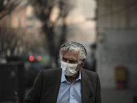 An Iranian elderly man wearing a protective face mask crosses an avenue in northern Tehran during a polluted air, following the COVID-19 out...