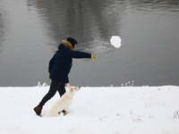 A man plays with his dog with snow in Krakow, Poland. January 14, 2021.  (