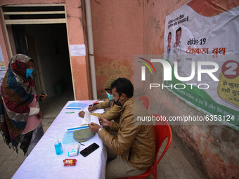 Police officials check identity card of a health worker before get vaccinated,  at a hospital  in the outskirts of Allahabad on January 16,2...