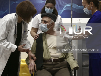 A doctor and nurses help an old man after his vaccination at Evaggelismos hospital on Athens on January 16, 2021 (Photo by Panayotis Tzamaro...
