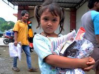 Refugee children showing food aid and blankets from aid at the Manakarra Stadium refugee post, Mamuju Regency, West Sulawesi Province, Indon...