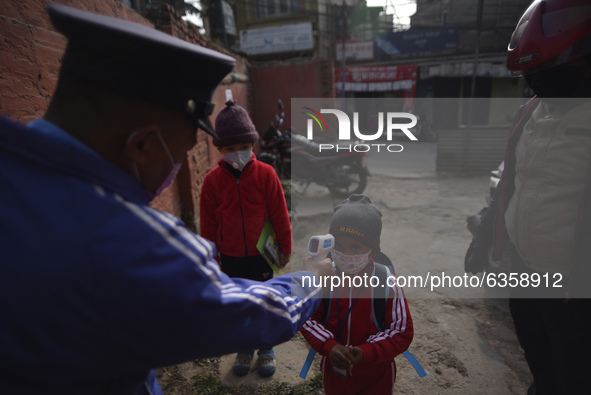 A School Security guard of Bagh Bhairab Boarding High School checking temperature and sanitizing students before entering classes due to COV...