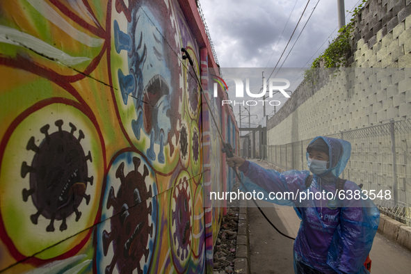 A man spray disinfectan to the mural wall. Mural Covid19 in Tangerang, Banten, Indonesia, on 26 January 2021. Indonesia reach out to 1 milli...