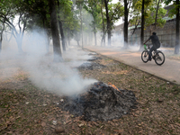 People seen moves as the garbage are burning beside a road in a park in Dhaka, Bangladesh, on March 13, 2021 (