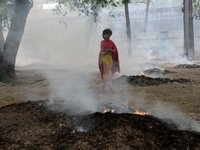 People seen moves as the garbage are burning beside a road in a park in Dhaka, Bangladesh, on March 13, 2021 (