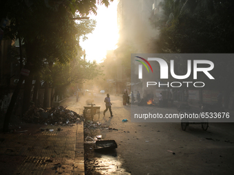 A pedestrian on move as construction workers working on a road that creates toxic smoke in Dhaka, Bangladesh on March 17, 2021. Air pollutio...