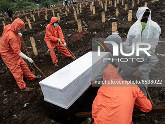 Grave digger put coffin to the grave.  Burrial process of a victim of Covid19 at Srengsawah, South Jakarta, Indonesia on March 19, 2021. Num...