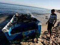 A Palestinian fishermen inspect their destroyed fishing boat hauled up onto the shore, close to the southern Gaza Strip town of Rafah, on th...