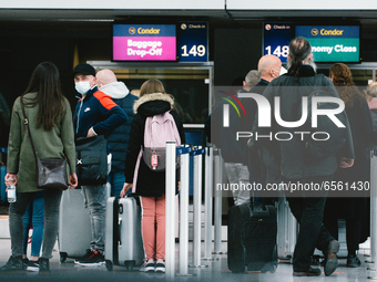 travellers wait in front of Condor check in counter at Duessedorf airport, Germany on March 26, 2021 as airlines adds more flights to cope w...
