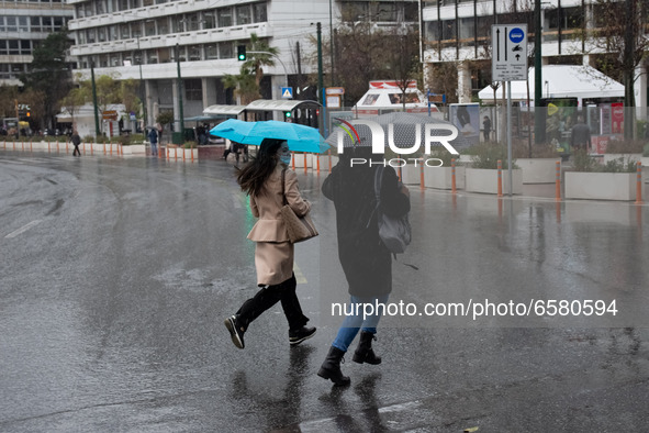 People seen wearing protected mask and holding umbrellas during a rainy day in Athens, Greece on April 1, 2021.  