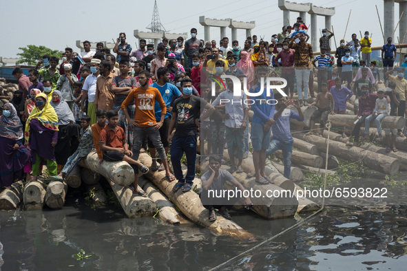 Local people and relatives gather as a rescue ship tries to recover a capsized boat in Shitalakshya River, in Narayanganj on April 5, 2021....
